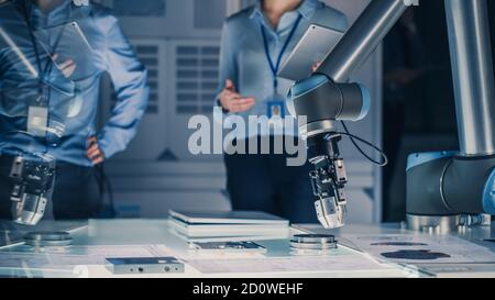 Futuristic Artificial Intelligence Robotic Arm Operates and Moves a Metal Object, Picks It Up or Puts it Down under Technician Control. High Tech Stock Photo