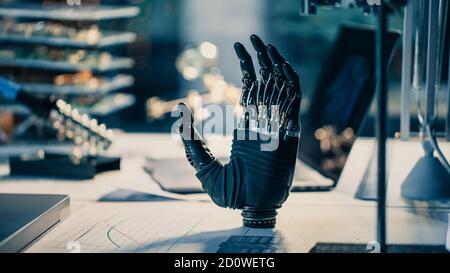 Close Up of a Futuristic Prosthetic Robot Arm Stands on a Desk in a High Tech Research Laboratory with Modern Computer Equipment. Stock Photo