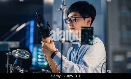 Futuristic Prosthetic Robot Arm Being Tested by a Professional Japanese Development Engineer in a High Tech Research Laboratory with Modern Computer