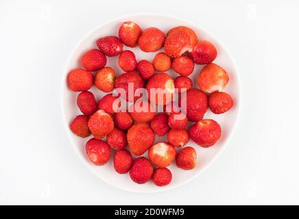Ripe strawberries without tails on a plate on a white background. Stock Photo
