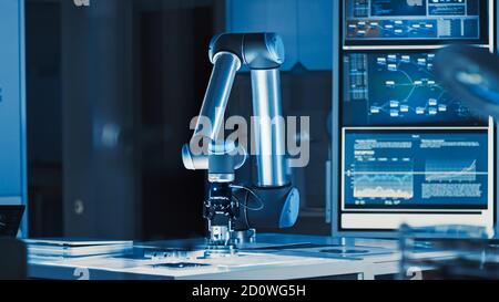 Futuristic Artificial Intelligence Robotic Arm Operates and Moves a Metal Object, Picks It Up and Puts it Down. Scene is Taken in a High Tech Research Stock Photo