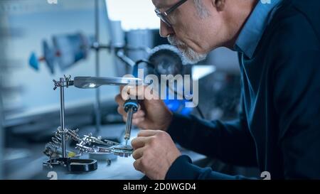 Portrait of Focused Middle Aged Engineer in Glasses Working with High Precision Laser Equipment, Using Lenses and Testing Optics for Accuracy Required Stock Photo