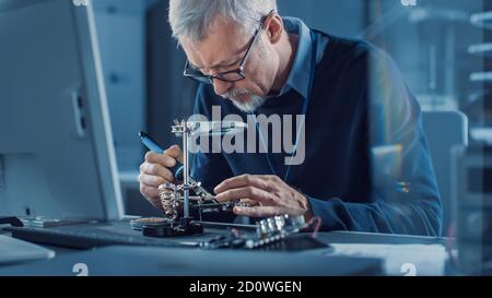 Electronics Maintenance Engineer Soldering Motherboard, Microchip and Circuit Board, Looking through Magnifying Glass, Consults Personal Computer Stock Photo