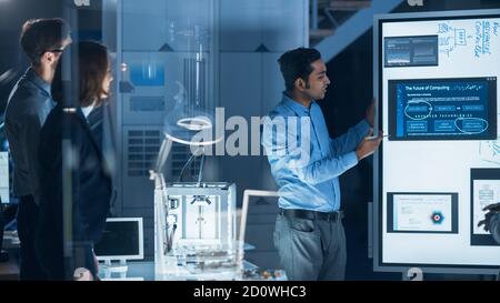 Engineers Meeting in Technology Research Laboratory: Male Engineer Leads Presentation Using Digital Whiteboard, Shows Machine Blueprint, Data Stock Photo