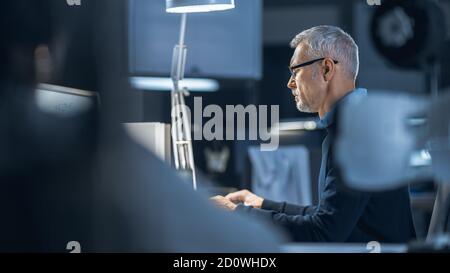 Shot of Industrial Engineer Working in Research Laboratory Development Center, Using Computer. He is Working on New Efficient Engine Concept Design. Stock Photo