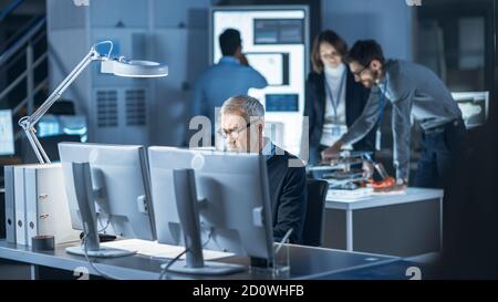 Shot of Industrial Engineer Working in Research Laboratory Development Center, Using Computer. In the Background Technology Development Laboratory Stock Photo