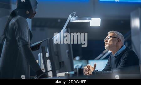 Shot of Male Industrial Engineer Talking with Female Manager about New Efficient Engine Concept Design. Diverse International Team of Industrial Stock Photo