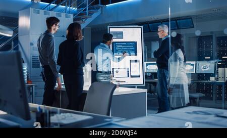 Engineers Meeting in Technology Research Laboratory: Male Engineer Leads Presentation Using Digital Whiteboard, Shows Machine Blueprint, Data Stock Photo