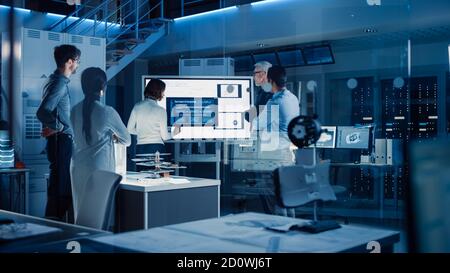 Engineers Meeting in Technology Research Laboratory: Female Engineer Leads Presentation Using Vertical Digital Whiteboard, Shows Machine Blueprint Stock Photo