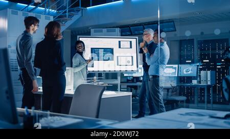 Engineers Meeting in Technology Research Laboratory: Male Engineer Leads Presentation Using Digital Whiteboard, Shows Machine Blueprint, Data Stock Photo