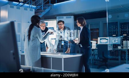 Engineers Meeting in Robotic Research Laboratory: Engineers, Scientists and Developers Gathered Around Illuminated Conference Table, Talking, Using Stock Photo