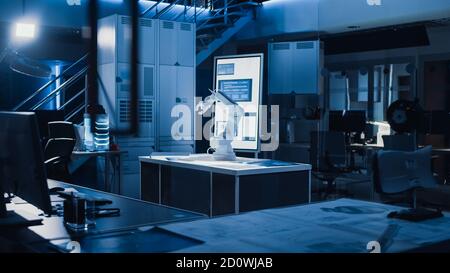 In Industrial Robot Desing Research Laboratory: Robotic Arm Prototype Standing Illuminated on the Desk. In the Dark Background Various High Tech Stock Photo