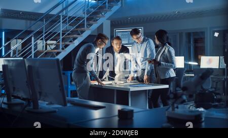 Team of Electronics Development Engineers Standing at the Desk Working on Robot Arm Prototype. Specialists Working on Ultra Modern Industrial Design Stock Photo