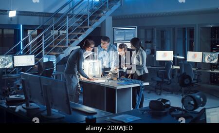 Diverse Team of Electronics Development Engineers Standing at the Desk with 3D Printer and PCB Motherboards. Specialists Collectively Working on Stock Photo