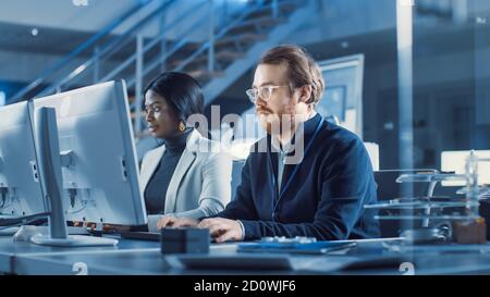Two Electronics Development Engineers Working on Computers. Team of Professionals Use CAD Software for the Modern Industrial Engineering Design. In Stock Photo