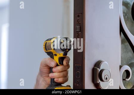 Locksmith in installing new house door lock hand holds the screwdriver Stock Photo