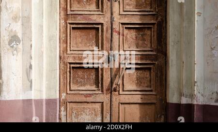Abandoned old door with the lock. Rust on the metal lock. Peeling brown paint on the old door. Stock Photo