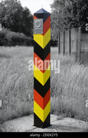 Historic German Democratic Republic (GDR, East Germany) border column. Former Inner German border. In the background the border fence. Stock Photo