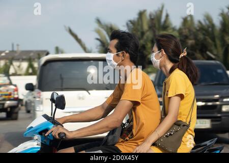 SAMUT PRAKAN, THAILAND, APR 27 2020,  A pair with protection mask on face rides on a motorbike on the city street. Stock Photo