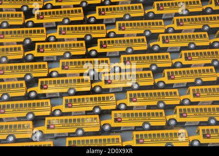 Grid of Toy Model School Buses in New York City yellow bus 7 rows high stop signs on sides black tires Stock Photo