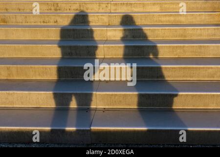 Blurry shadow, silhouette of two people standing next to outdoor steps Stock Photo