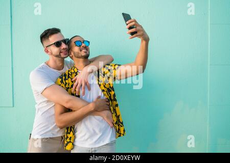 Portrait of happy gay couple spending time together and taking a selfie with mobile phone. Lgbt and love concept. Stock Photo
