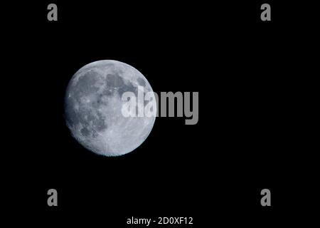 Almost full moon on a dark black sky Stock Photo