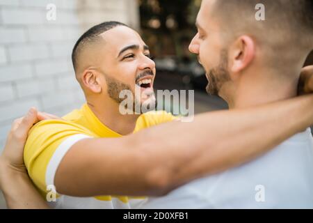 Portrait of happy gay couple spending time together and hugging in the street. Lgbt and love concept. Stock Photo
