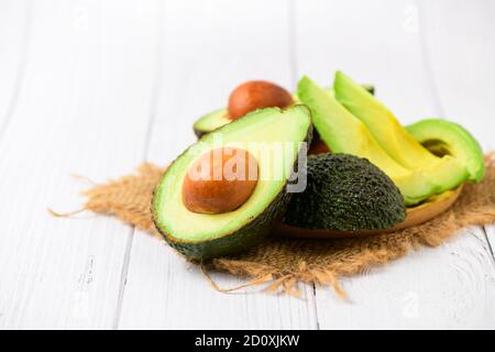 Avocado on wood plate and white wood background. Ripe fresh green avocado Stock Photo