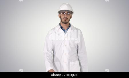 Young engineer in robe and helmet putting glasses on while walki Stock Photo