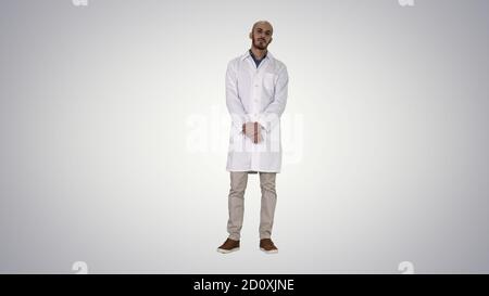 Standing young serious arab doctor on gradient background. Stock Photo