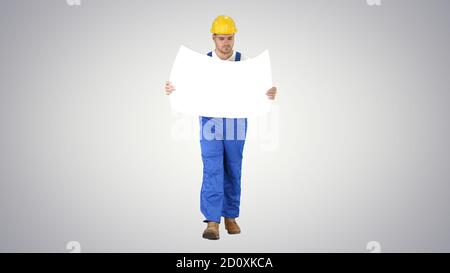 Thoughtful builder in helmet looking at blueprint and walking on Stock Photo
