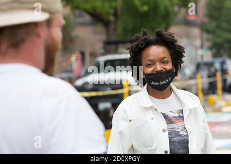 Seattle, Washington, USA. 3RD October, 2020. Artist Takiyah Ward (in all white) with the Vivid Matter Collective speaks with a cohort during restoration work on the Black Lives Matter mural in Seattle’s Capitol Hill neighborhood. The collective of of Black and Indigenous artists created the original street mural during the Capitol Hill Occupied Protest in June. They collaborated with the City of Seattle's Office of Arts and Culture to restore the mural and make it a permanent landmark. Credit: Paul Christian Gordon/Ģ����ý Live News Stock Photo