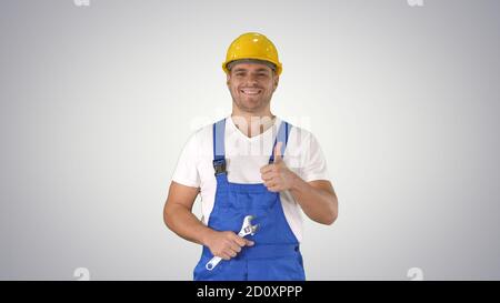 Worker with wrench showing thumb up and smiling to camera on gra Stock Photo