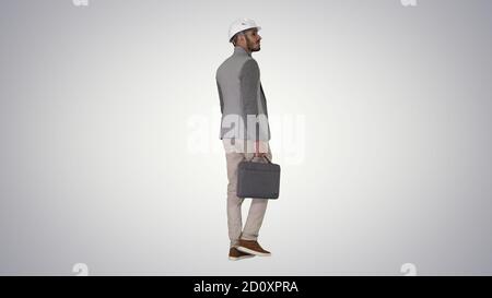 Engineer in helmet with briefcase walking on gradient background Stock Photo