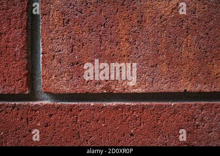 A landscape-orientation close-up image of red bricks in a wall shows texture, detail and perpendicular lines. Stock Photo