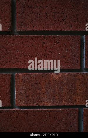 A portrait-orientation close-up image of red bricks in a wall shows texture and detail. Stock Photo