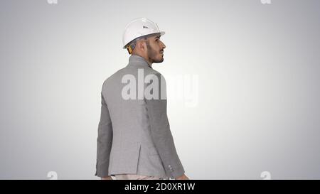 Engineer in helmet with briefcase walking on gradient background Stock Photo