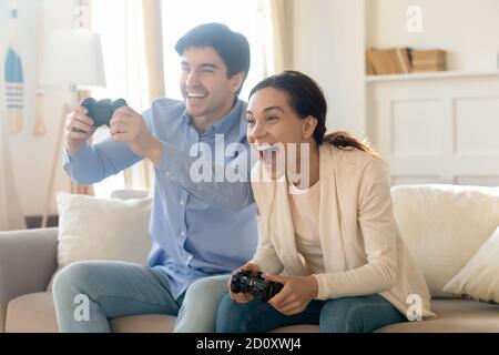 Excited emotional young family married couple playing console video games Stock Photo