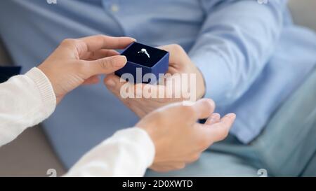 Young woman taking engagement ring from man hand accepting proposal Stock Photo