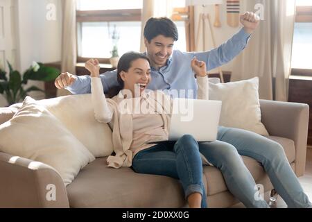 Happy yelling young spouses getting email of winning lottery jackpot Stock Photo