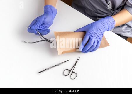Master of manicure in gloves put tools in paper bag for sterilizing Stock Photo