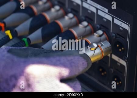 Sound engineer plugging audio cable on studio system boxes. Stock Photo