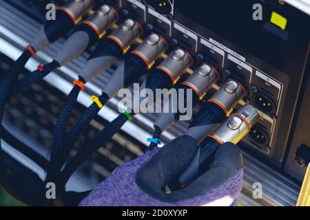 Sound engineer plugging audio cable on studio system boxes. Stock Photo