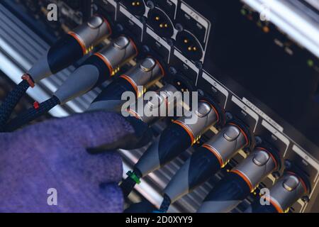 Sound engineer plugging audio cable on studio system boxes. Stock Photo