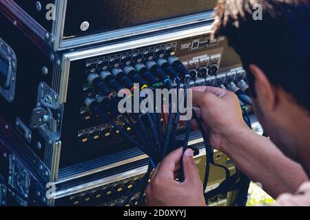 Sound engineer plugging audio cable on studio system boxes. Stock Photo