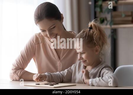 Smiling mother and little daughter playing wooden board game Stock Photo
