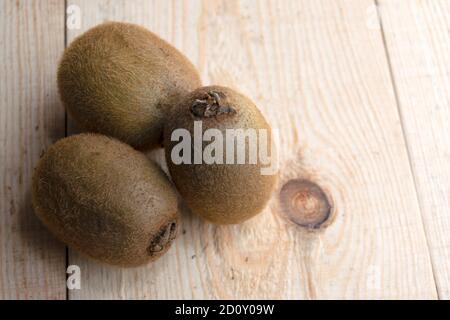 three kiwis are lying on a wooden table Stock Photo