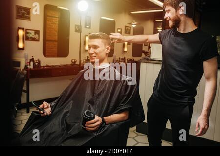 Chatty hairdresser talking to a client in chair about haircut final adjusments. Stock Photo
