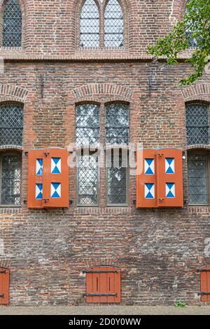 Historic Dutch castle wall with windows with stained glass and multicolored wooden shutters Stock Photo